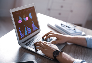 Broker using laptop at table indoors, closeup. Forex trading