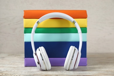 Photo of Modern headphones with hardcover books on wooden table