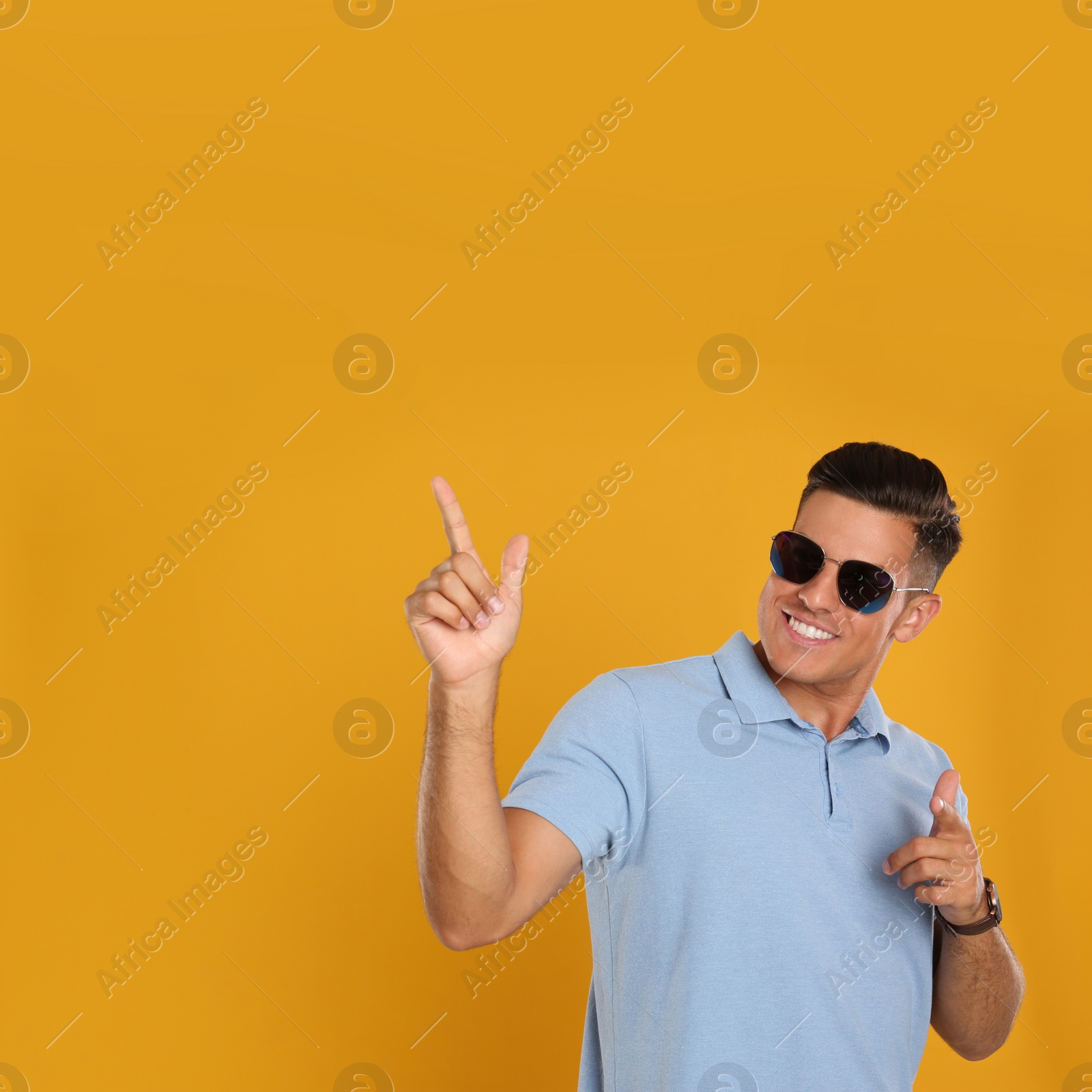 Photo of Handsome man wearing sunglasses on yellow background