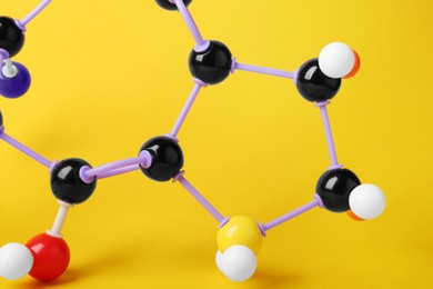 Photo of Structure of molecule on yellow background, closeup. Chemical model