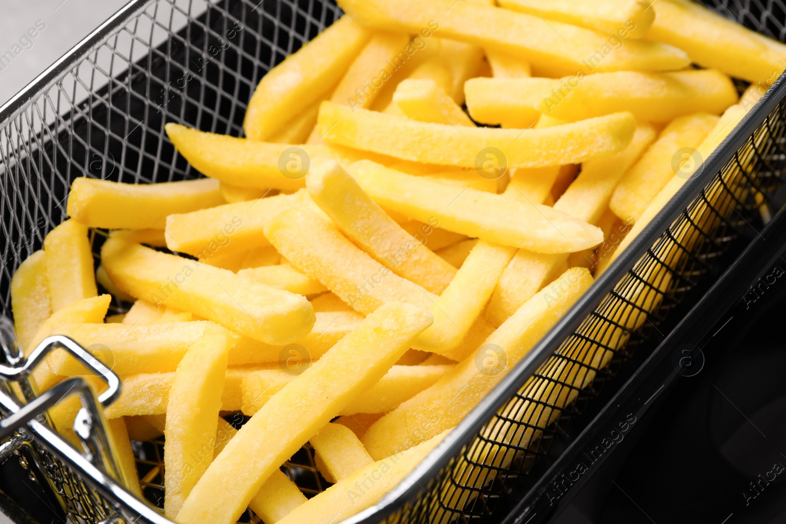 Photo of Uncooked french fries in metal basket, closeup