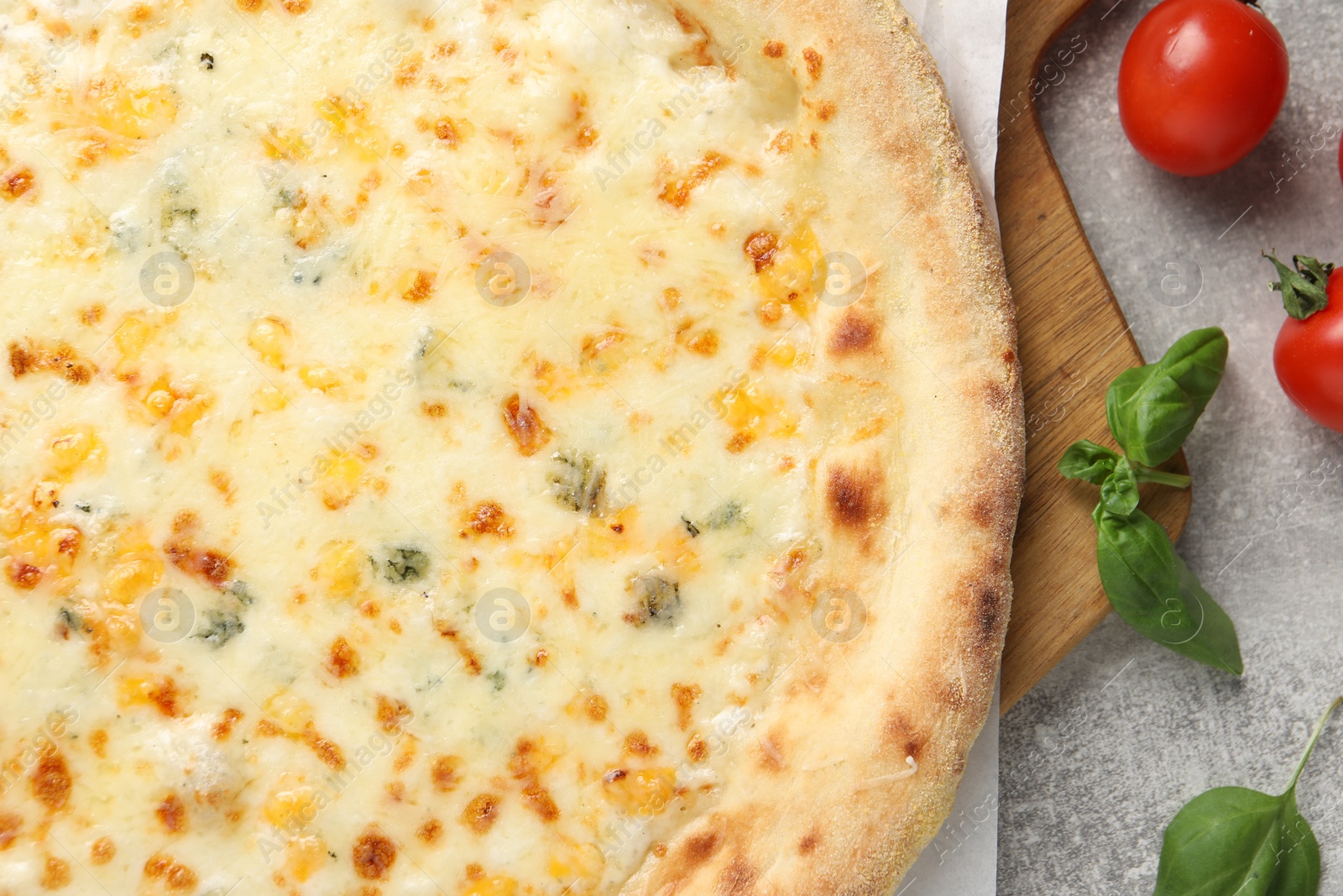 Photo of Delicious cheese pizza, basil and tomatoes on light grey table, flat lay