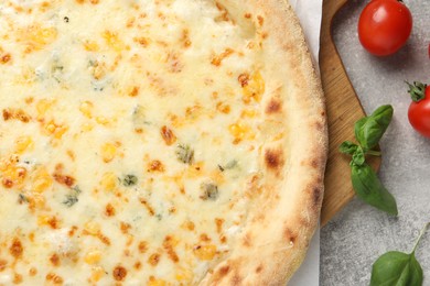 Delicious cheese pizza, basil and tomatoes on light grey table, flat lay