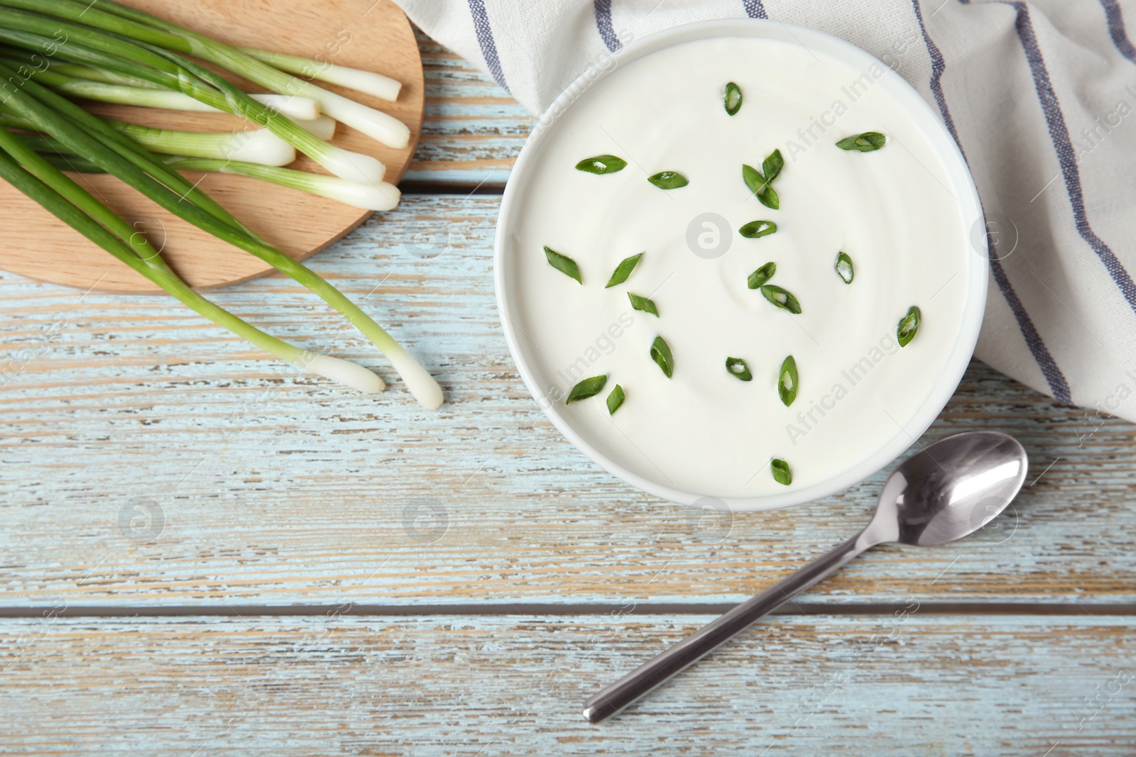 Photo of Flat lay composition with sour cream and green onion on light blue wooden table, space for text