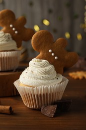 Tasty Christmas cupcakes with gingerbread man cookies on wooden table