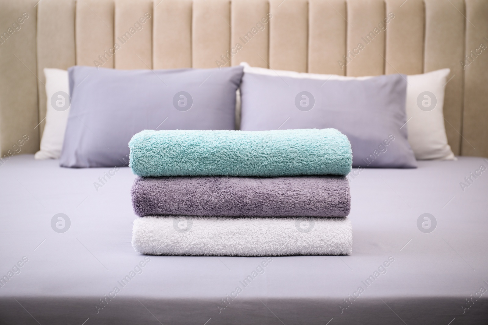 Photo of Stack of soft clean terry towels on bed