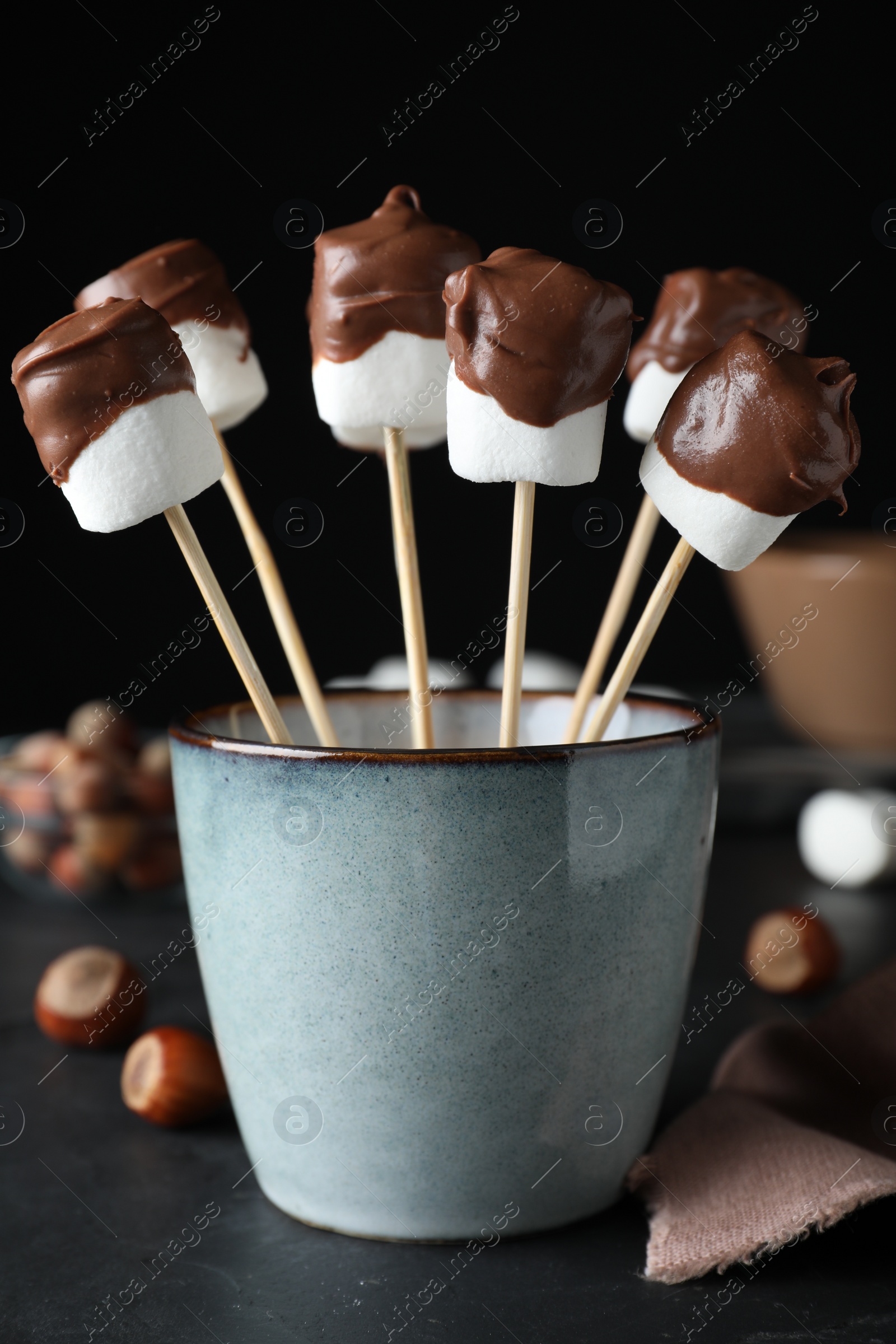 Photo of Delicious marshmallows covered with chocolate on black table