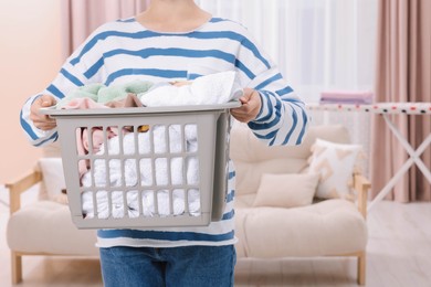 Photo of Woman with basket full of laundry at home, closeup