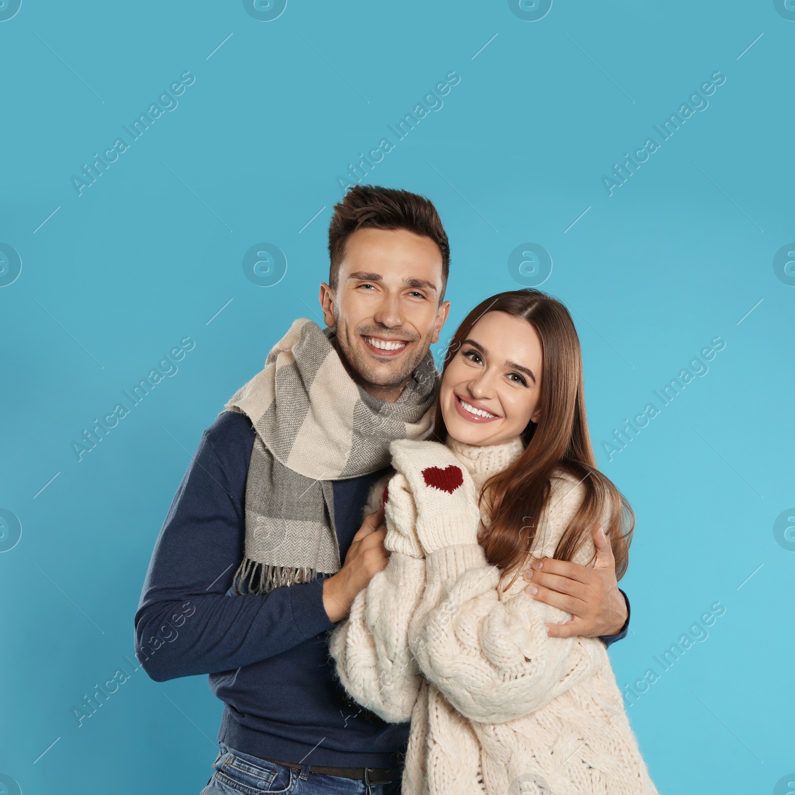 Photo of Happy young couple in warm clothes on blue background. Winter season