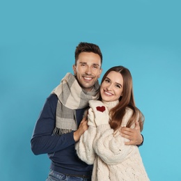 Photo of Happy young couple in warm clothes on blue background. Winter season