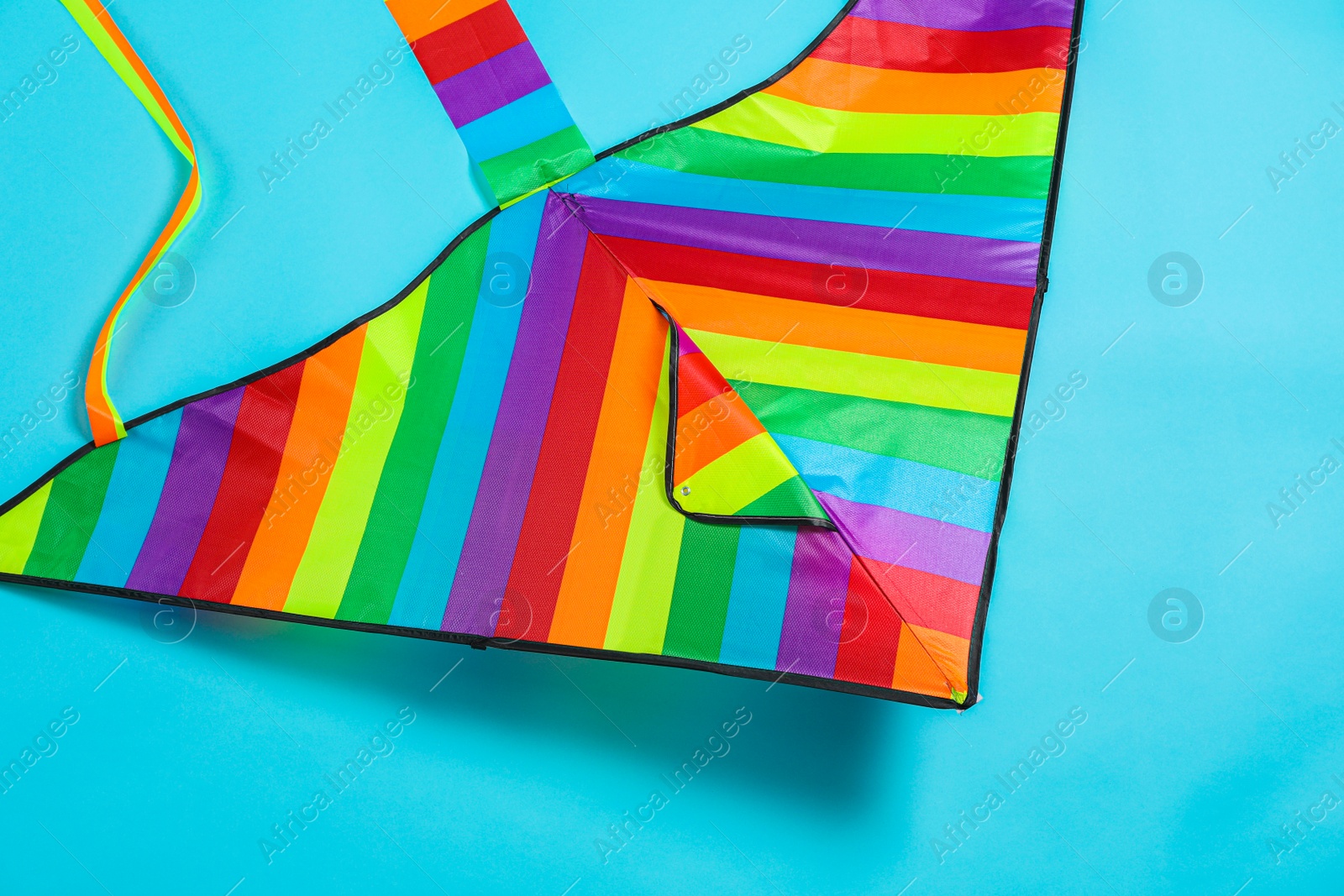 Photo of Bright rainbow kite on light blue background, top view