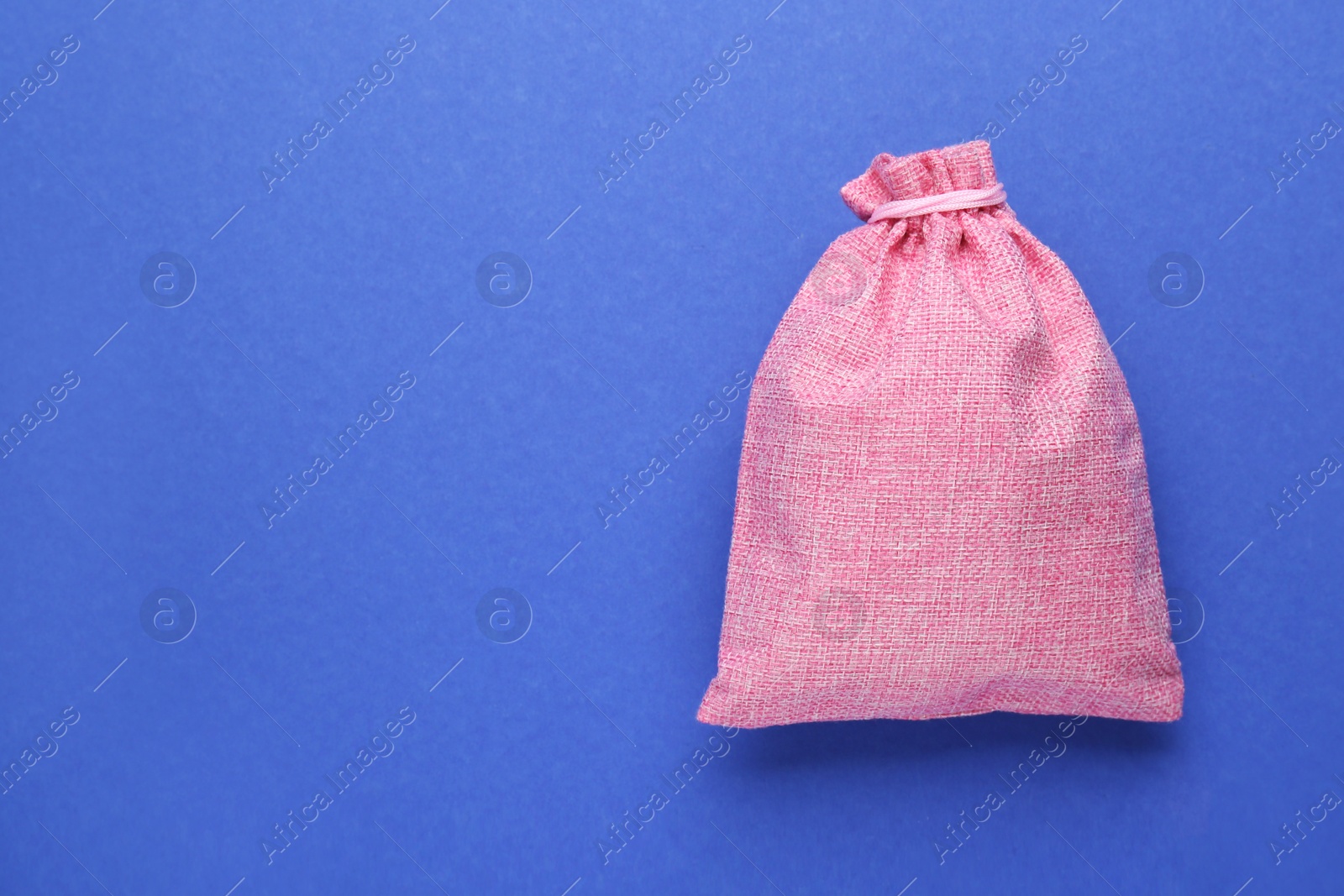 Photo of Pink burlap bag on blue background, top view. Space for text