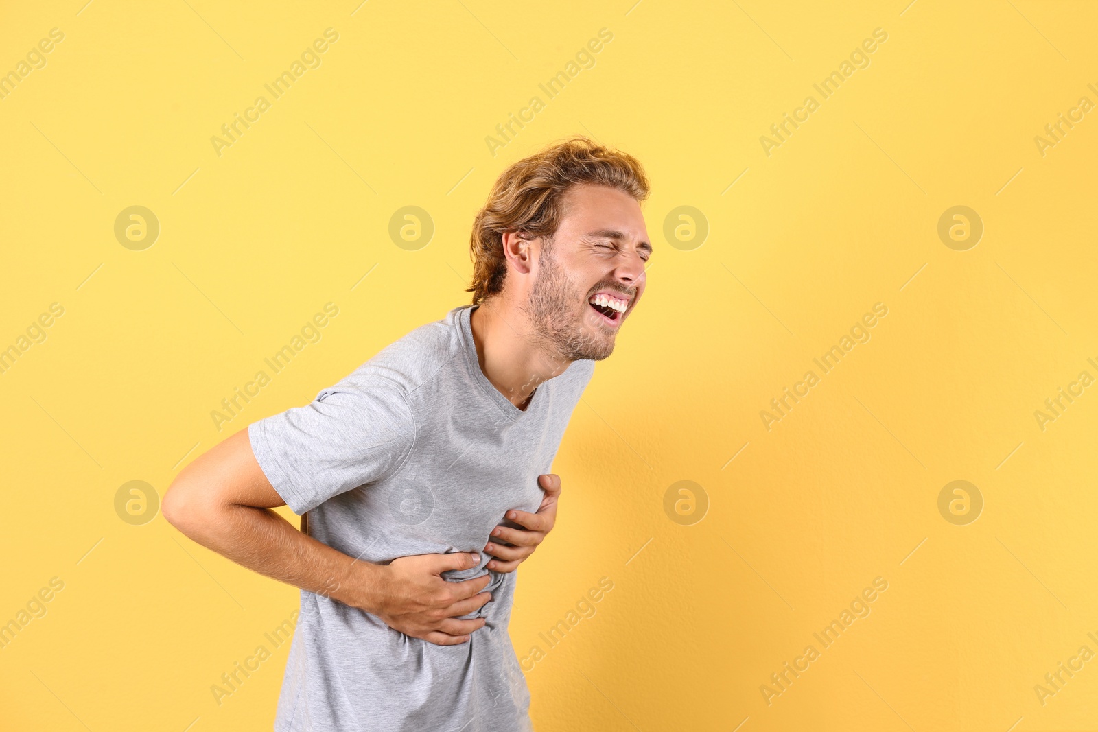 Photo of Handsome young man laughing on color background