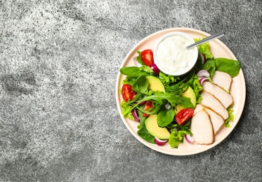 Photo of Delicious salad with chicken, arugula and avocado on grey table, top view. Space for text