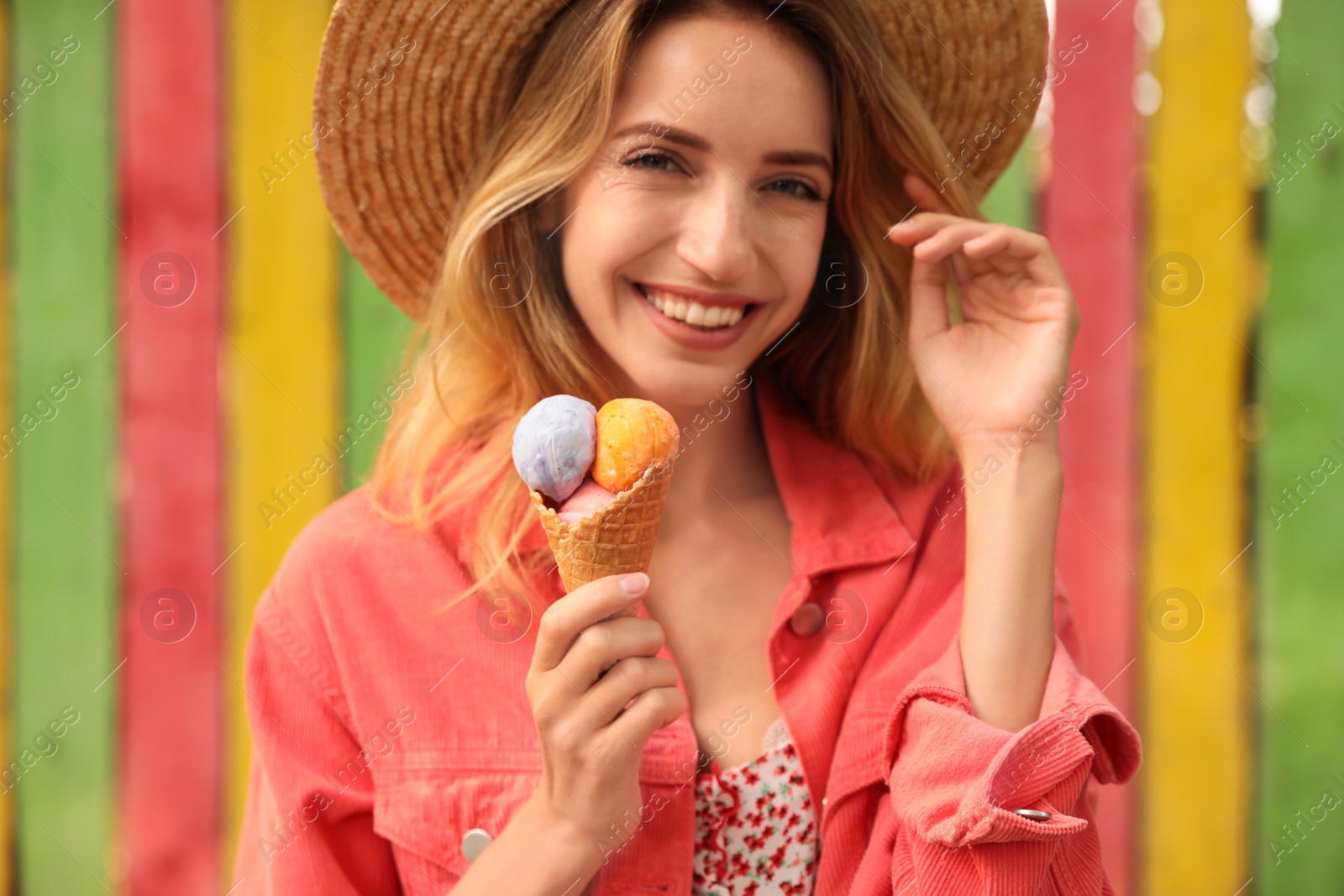 Photo of Happy young woman with delicious ice cream in waffle cone outdoors