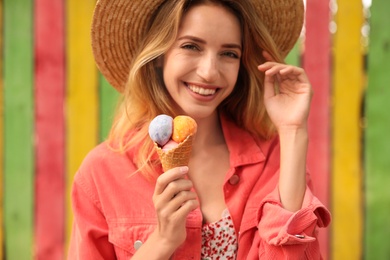 Photo of Happy young woman with delicious ice cream in waffle cone outdoors