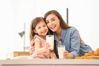 Photo of Mother and daughter having breakfast with milk at table