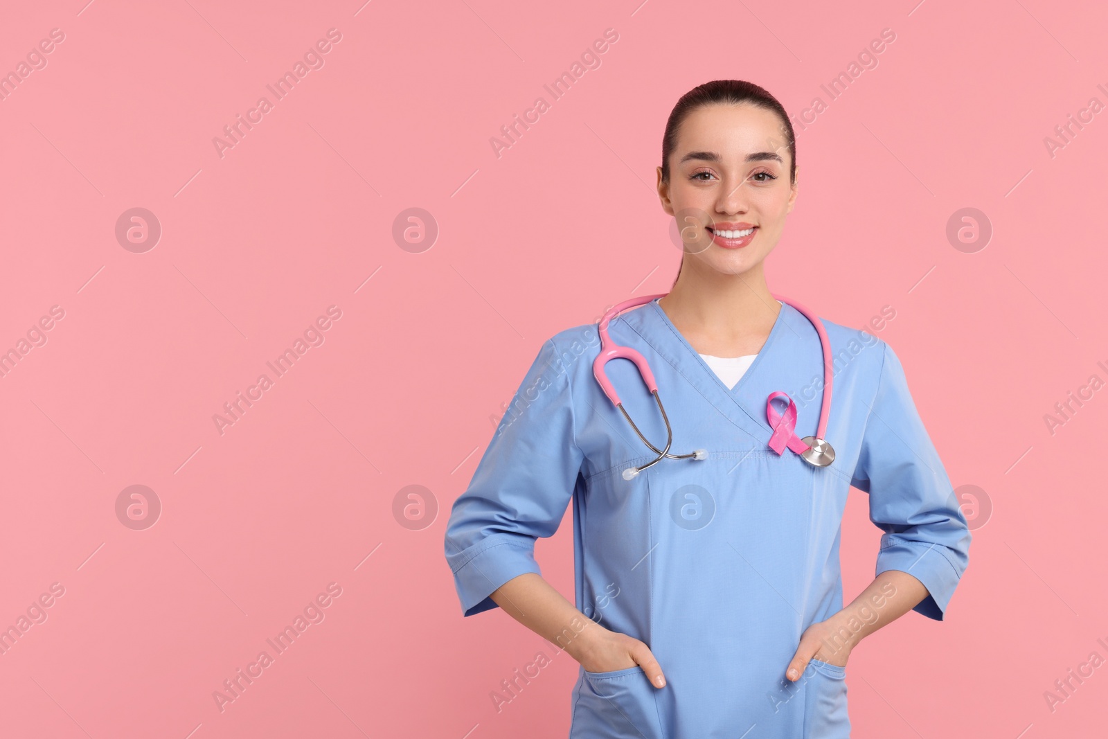 Photo of Mammologist with pink ribbon on color background, space for text. Breast cancer awareness