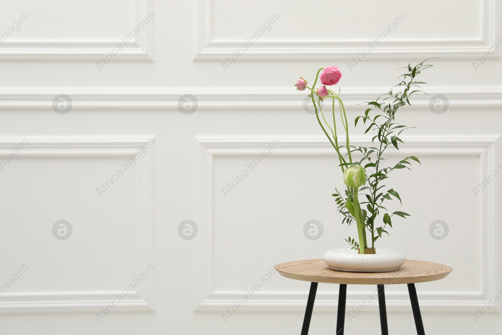 Photo of Ikebana art. Beautiful pink flowers and green branch carrying cozy atmosphere at home, space for text