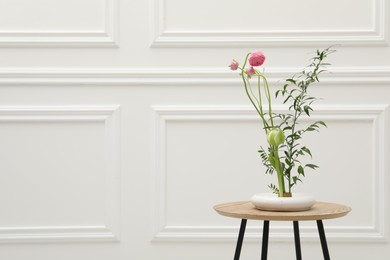 Ikebana art. Beautiful pink flowers and green branch carrying cozy atmosphere at home, space for text