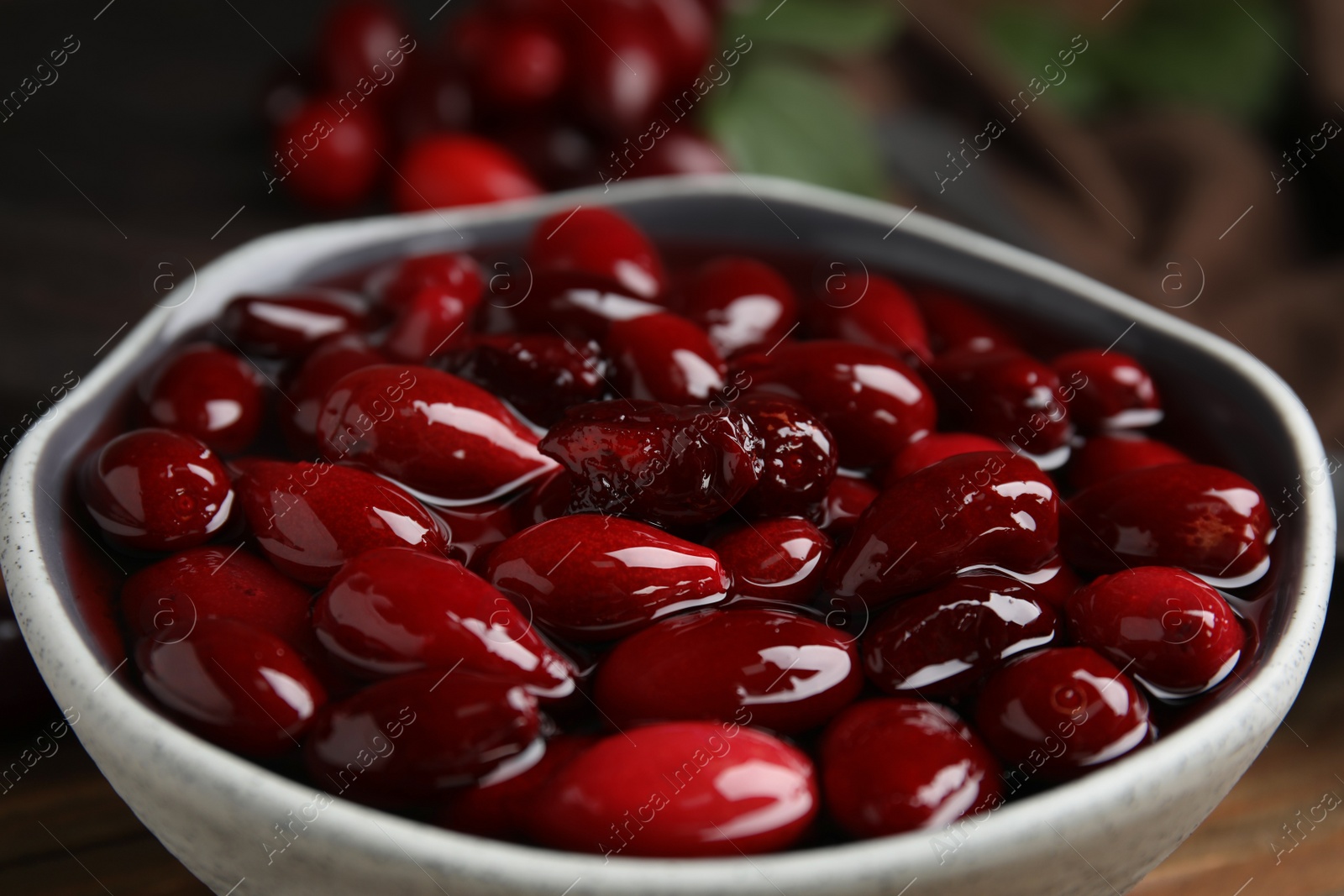 Photo of Delicious dogwood jam with berries in bowl on table, closeup