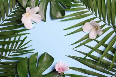 Photo of Flat lay composition with tropical leaves and Hibiscus flowers on blue background