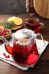 Tasty hot cranberry tea in teapot and fresh berries on wooden table