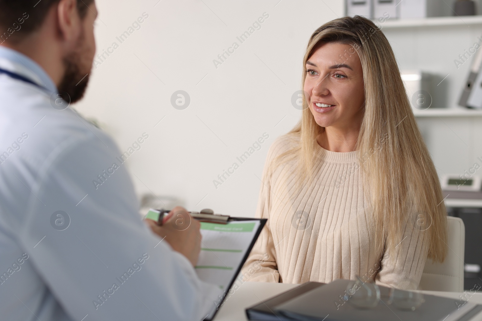 Photo of Professional doctor working with patient at white table in hospital