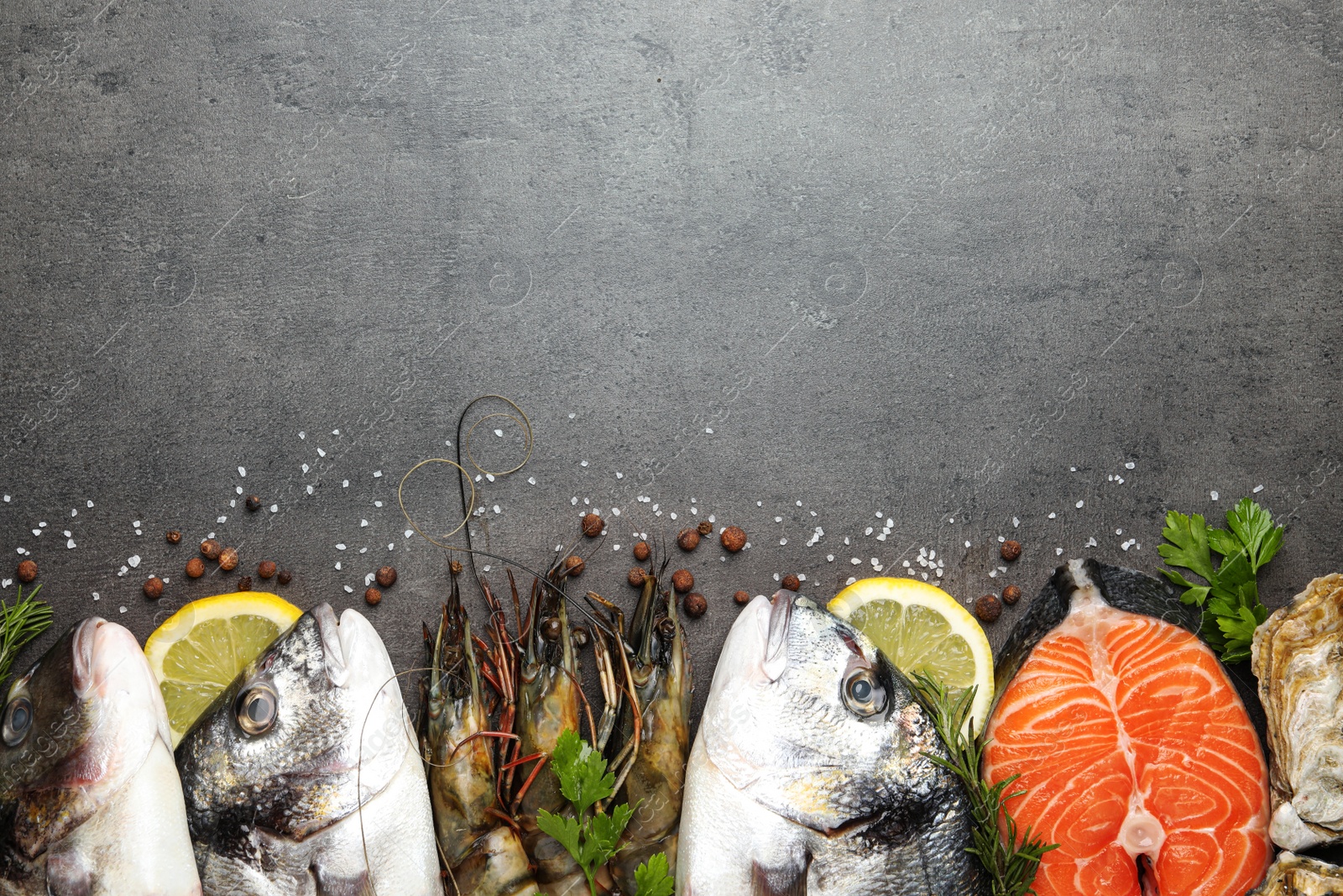 Photo of Flat lay composition with fresh raw dorado fish and different seafood on grey table. Space for text