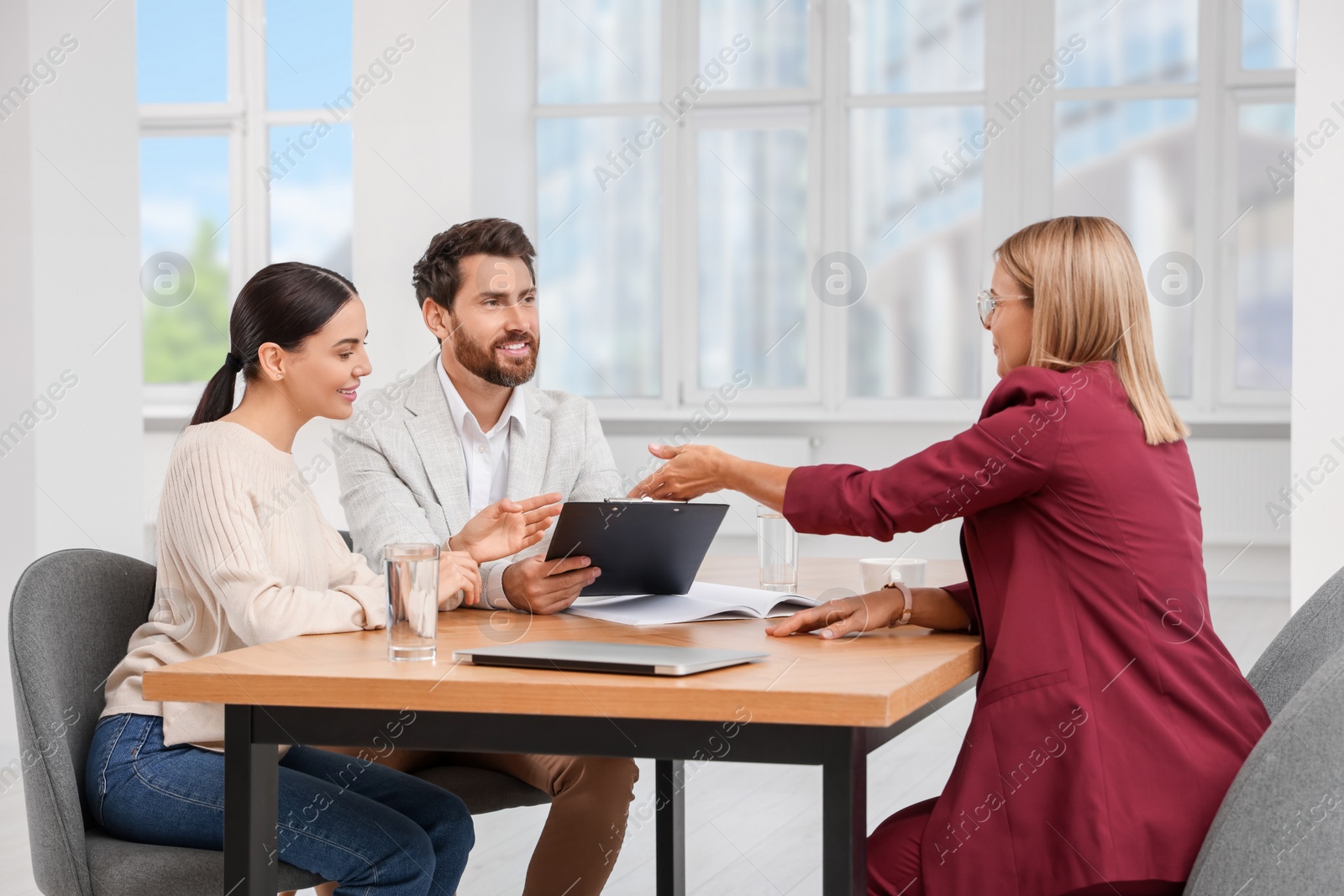 Photo of Real estate agent giving key to couple at table in new apartment