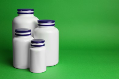 Photo of Many different plastic medicine bottles on green background, space for text. Medicament