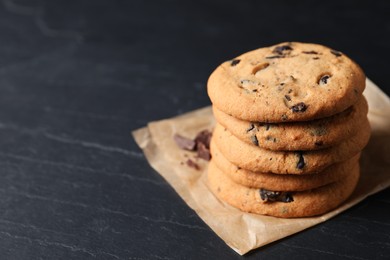 Photo of Delicious chocolate chip cookies on black table. Space for text