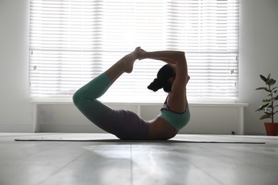 Woman practicing bow asana in yoga studio. Dhanurasana pose
