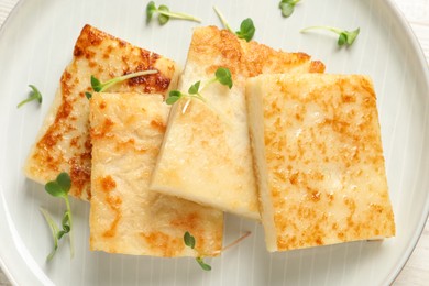 Photo of Delicious turnip cake with microgreens on plate, top view