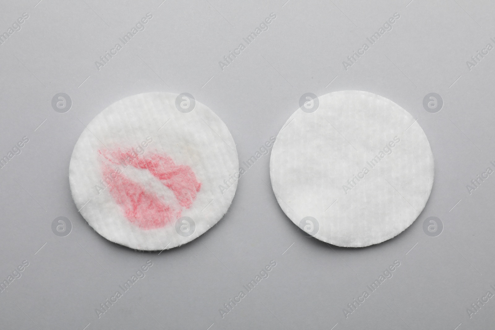 Photo of Clean and dirty cotton pads after removing makeup on light grey background, flat lay