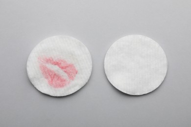 Clean and dirty cotton pads after removing makeup on light grey background, flat lay