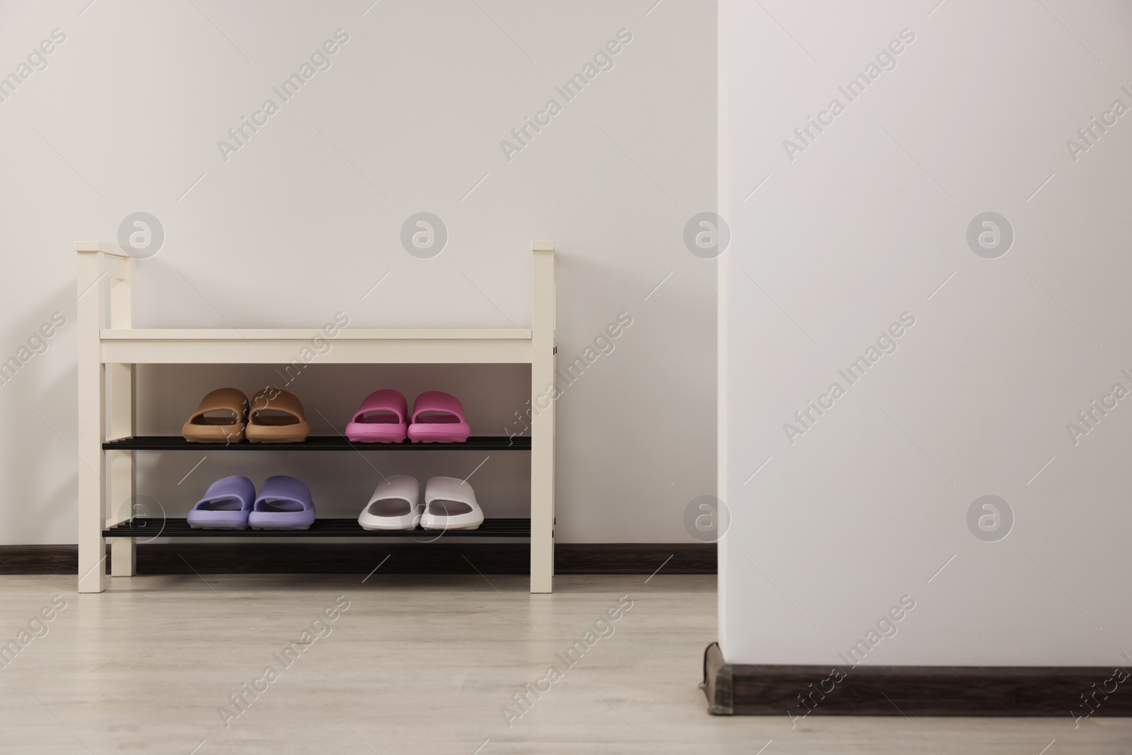 Photo of Storage bench with pairs of rubber slippers indoors