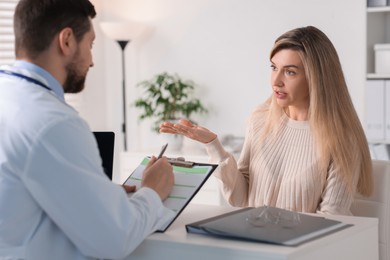 Professional doctor working with patient at white table in hospital