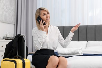 Photo of Smiling businesswoman talking on smartphone in stylish hotel room
