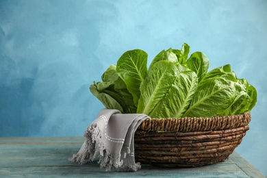 Wicker basket with fresh ripe cos lettuce on wooden table