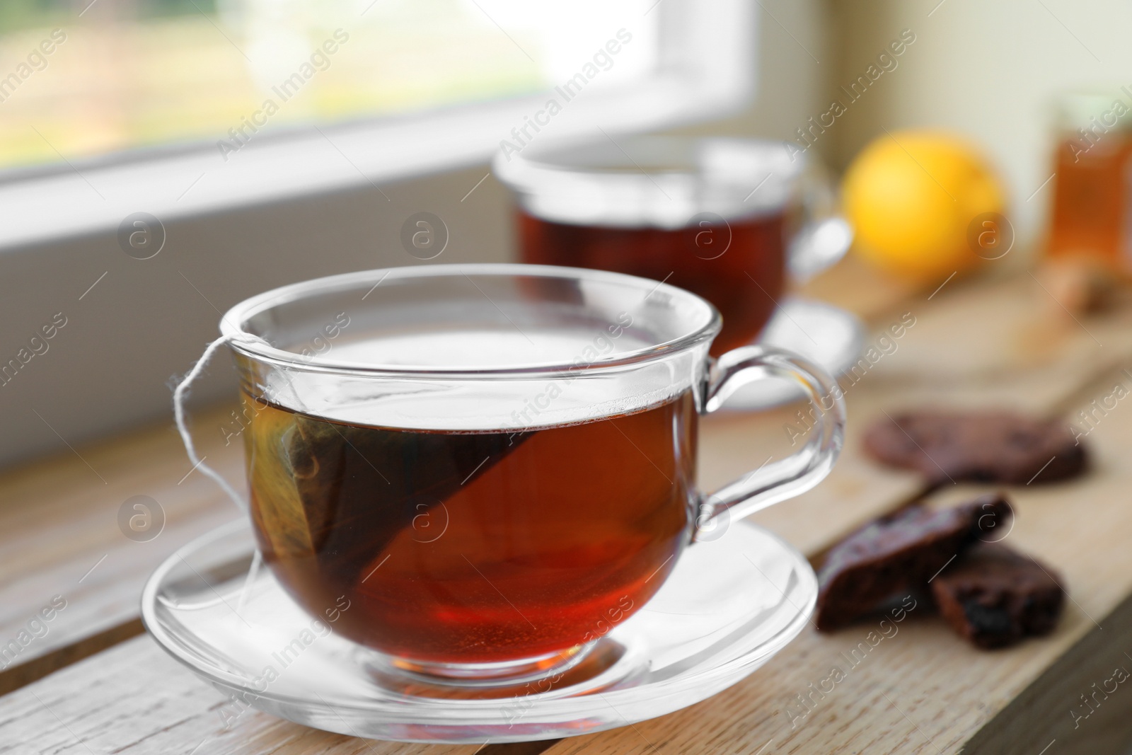 Photo of Bag of black tea in cups on wooden table indoors