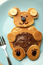 Creative serving for kids. Plate with cute bear made of pancakes, blueberries, bananas and chocolate paste, top view