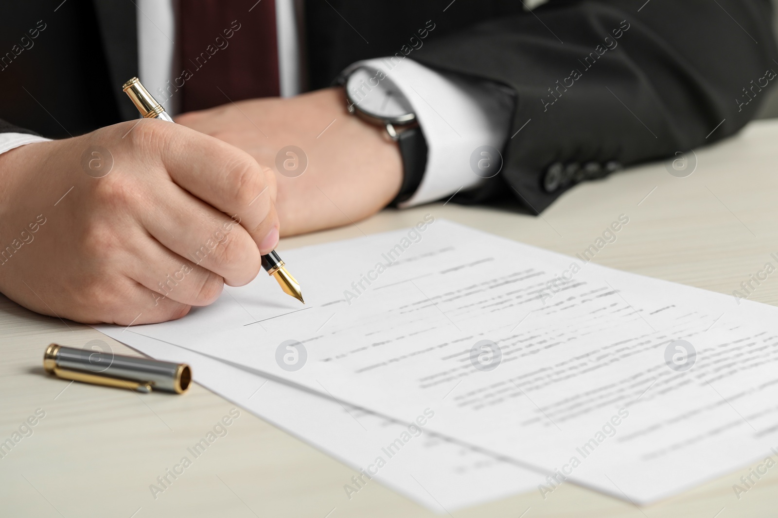 Photo of Notary signing document at wooden table, closeup