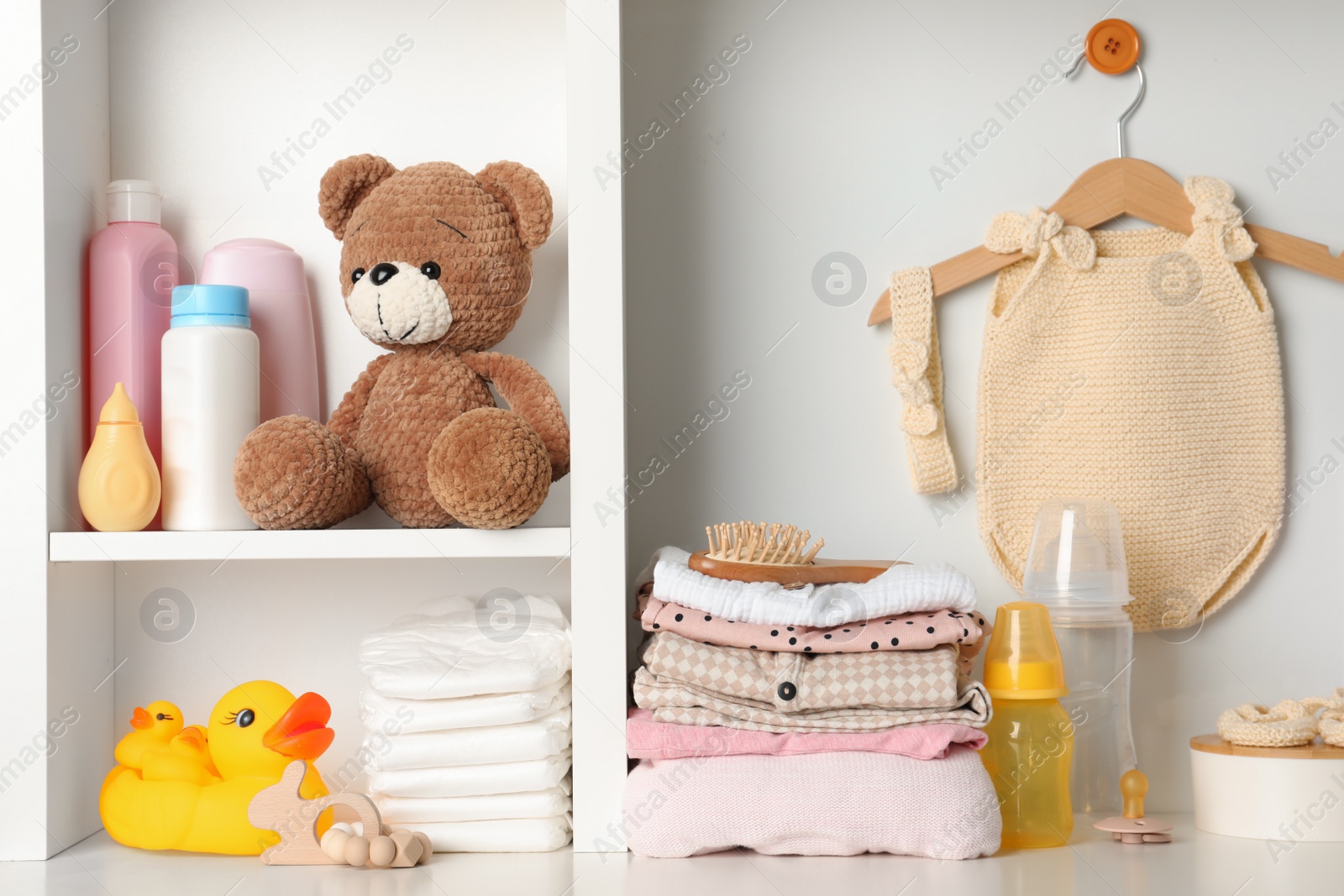 Photo of Baby clothes, toys and accessories on white rack