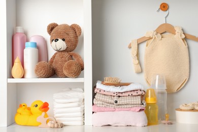 Baby clothes, toys and accessories on white rack