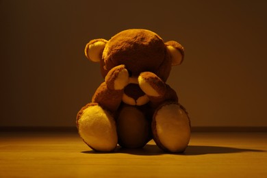 Cute lonely teddy bear on floor in dark room