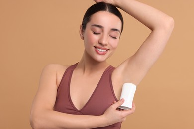 Photo of Beautiful woman applying deodorant on beige background