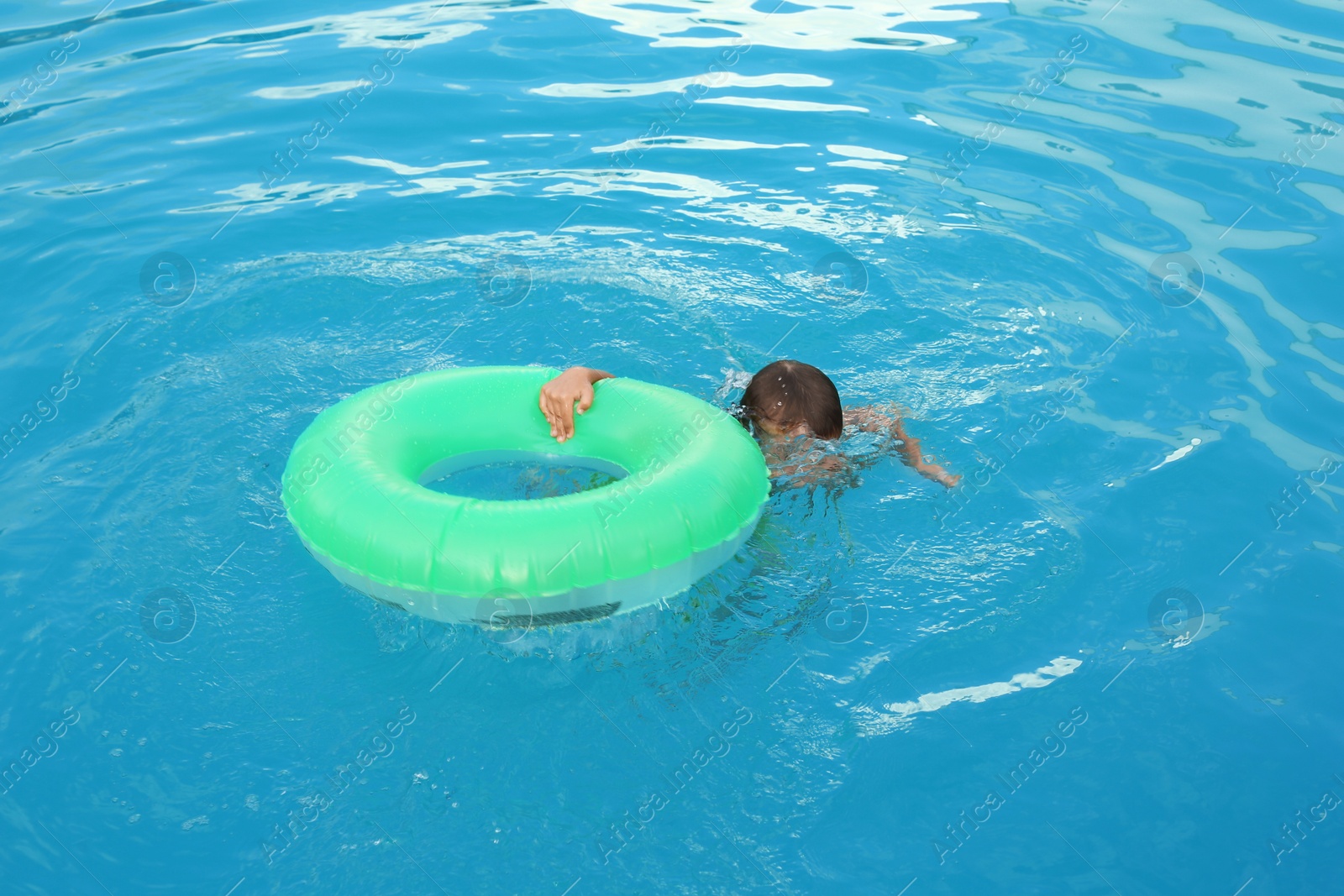 Photo of Little child with inflatable ring in outdoor swimming pool. Dangerous situation