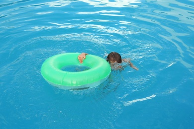 Photo of Little child with inflatable ring in outdoor swimming pool. Dangerous situation