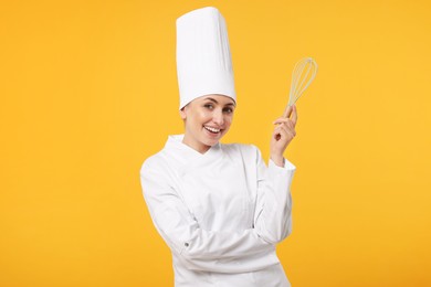 Photo of Happy professional confectioner in uniform holding whisk on yellow background